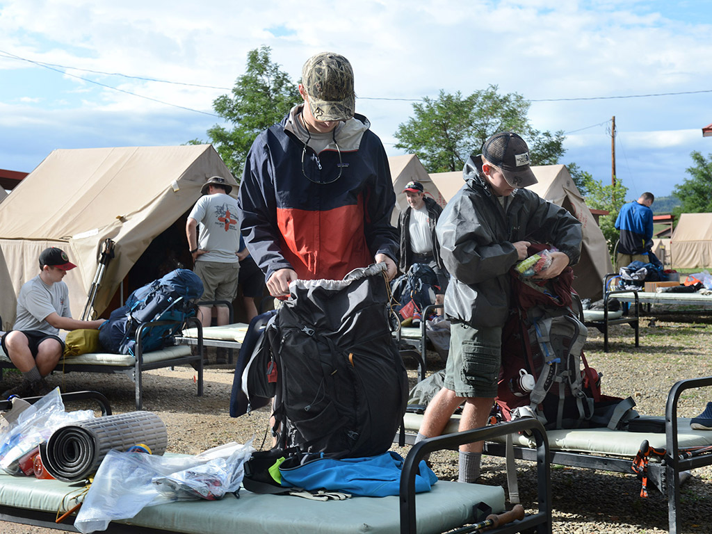 Students with backpacks rested on their outdoor cots, begin packing up